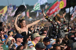 Festival-goers sit on each other's shoulders in a crowd at Glastonbury 2023