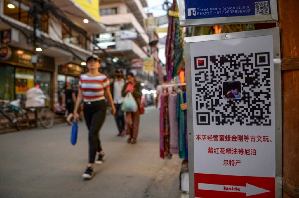 Κινέζοι τουρίστες περνούν δίπλα από έναν κωδικό QR.